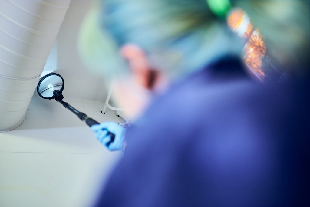 En person håller i ett förstoringsglas med glasdelen mot en fog i taket.