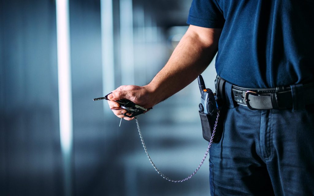 Univormuun pukeutuneen henkilön käsi, jossa on avainnippu.