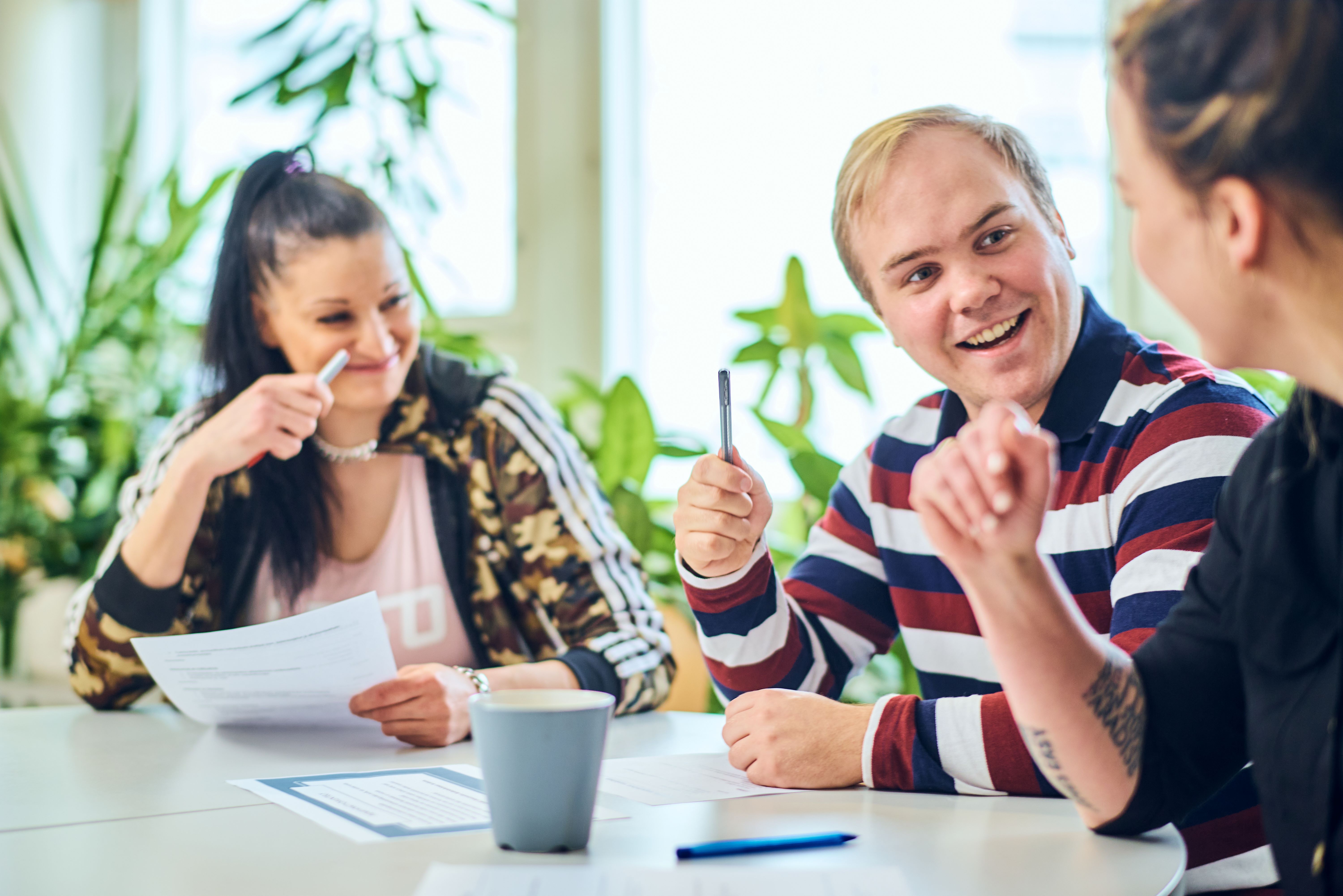 RSKk vartijaopiskelijoita istumassa pöydän äärellä keskustellen papereita ja kyniä edessään.